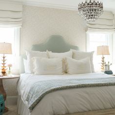 a bedroom with a chandelier hanging from the ceiling and pillows on the bed