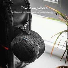 a black bag hanging from the side of a window sill next to a potted plant