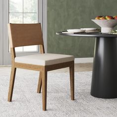 a dining room table with two chairs and a bowl of fruit on the table next to it