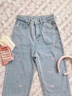 a pair of blue jeans with hearts on them next to a hair clip and comb