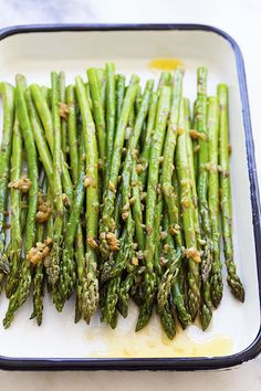 asparagus spears on a white plate with lemon juice and seasoning sprinkles