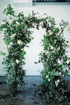 an arch covered in white flowers and greenery