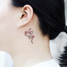 a woman with a small tattoo on her neck and behind her ear is a flower