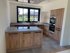 an empty kitchen with wooden cabinets and black windows