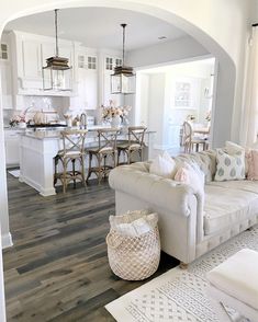 a living room filled with furniture next to a kitchen and dining room table on top of a hard wood floor