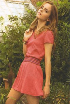 a young woman in a pink dress posing for a photo with her hand on her shoulder