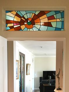 an open door leading to a living room with a stained glass window above the doorway