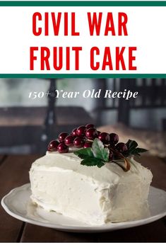 a white cake sitting on top of a wooden table next to a plate with berries