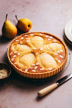 a pie sitting on top of a table next to a bowl of nuts and pears