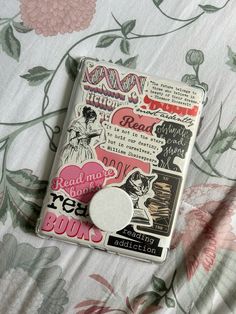 a book with some stickers on it laying on a flowery sheet covered bed