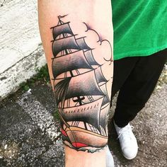 a man's arm with a ship tattoo on it