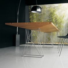 two black chairs and a wooden table in front of a wall with green plants on it