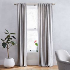 a living room with a chair, window and potted plant