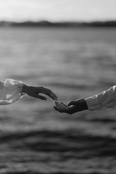 black and white photograph of two people reaching out to touch each other's hands