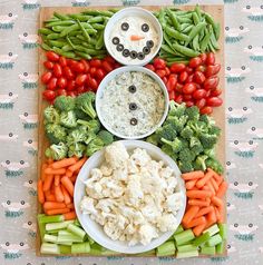 a platter with vegetables, dips and snowman faces on it's sides