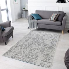 a living room with two chairs and a rug on the floor in front of a couch