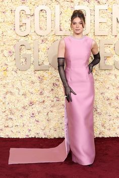 a woman in a pink dress and black gloves on the red carpet at an event