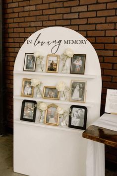 an arch with pictures and flowers on it is displayed in front of a brick wall