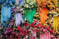 colorful flowers and streamers are arranged on the side of a wall in rainbow colors