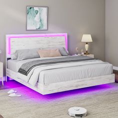 a white bed with purple lights on the headboard and foot board in a bedroom