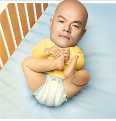 a bald man sitting on top of a blue bed next to a baby crib