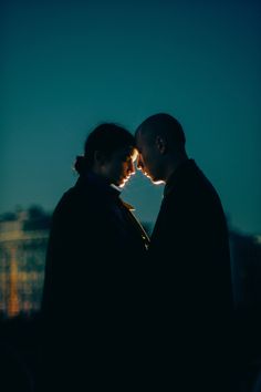 two people standing next to each other with their faces close together in the night sky