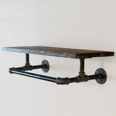 an industrial style shelf with pipes attached to it and two hooks on the wall above