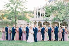 a large group of people in formal wear posing for a photo on the grass near a building