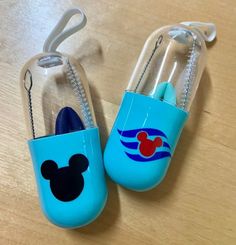 two blue mickey mouse air freshener holders on a wooden table with silver chain attached to them