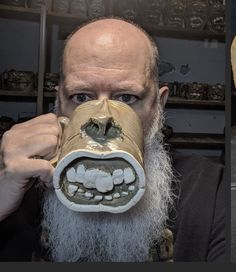 a man with a fake mouth and teeth on his face is holding up a coffee mug