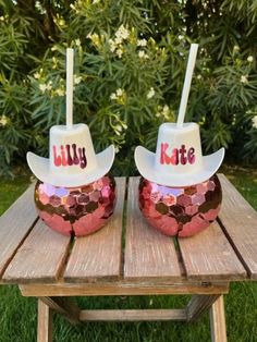 two cups with straws in the shape of cowboy hats are sitting on a picnic table