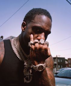 a man with tattoos on his arm holding two rings in front of his face while standing next to a car