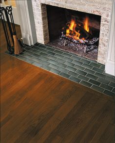 a fireplace with a fire burning in it and wood flooring on the other side