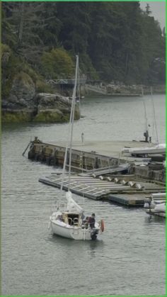 a small sailboat in the water next to a dock