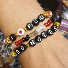 "The I Love FSU Go Noles Beaded Word Bracelet was made using 4mm glass seed beads, 6mm crystal bicone beads, and heishi clay beads. The words \"I ♡ FSU\" and \"GO NOLES\" are spelled out on black round letter beads in white letters.  Bracelets are all HANDMADE with love and care by myself, Candice Marie, and they are always limited edition and one-of-a-kind. ❤️ The bracelet is stretchy and stackable and looks great stacked with other Candice Marie Bead Co. beaded word bracelets in my shop! :) Be Casual Flexible Beaded Bracelets With Letter Beads, Team Spirit Bracelets With Letter Beads, School Spirit Letter Beads Bracelets Gift, Fsu Bracelet, Team-colored Sports Bracelets With Letter Beads, Word Bracelet, White Letters, Letter Beads, Heishi Beads