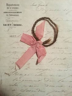 a pink ribbon tied to a piece of paper with writing on it and handwritten notes