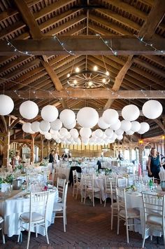 tables and chairs are set up with white paper lanterns hanging from the ceiling