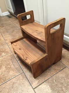 a wooden step stool sitting on top of a tile floor