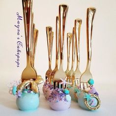 there are gold forks and spoons in the shape of cupcakes with seashells on them