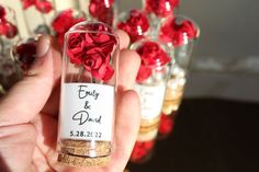 a person holding a tiny bottle with flowers in it and labeled wedding date on the label