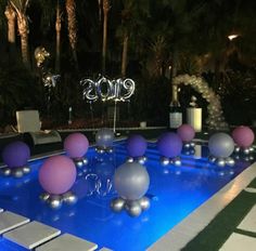 an outdoor pool decorated with balloons and streamers for a party or wedding in the evening