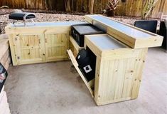 an outdoor kitchen is made out of wood and has drawers on each side, with the doors open