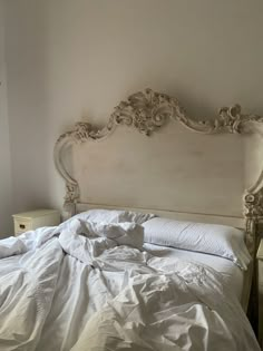 an unmade bed with white sheets and pillows