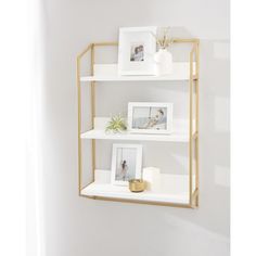 three white shelves with pictures and plants on them