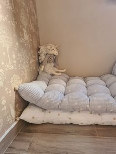 a stuffed animal sitting on top of a bed in a room with wall paper and pillows