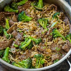 beef and broccoli stir - fry in a skillet with sesame seed noodles