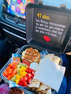 a lunch box filled with fruit, bread and crackers next to a cell phone