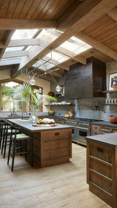 a large kitchen with wooden floors and an island in the center, surrounded by windows