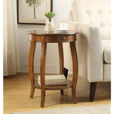 a small wooden table with a glass vase on it and a white chair in the background