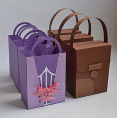 three different colored paper bags with handles and bows on the handles, one has a bow at the top